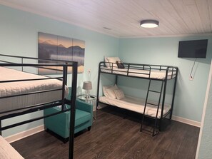 Ein Zimmer mit Etagenbetten, einem runden Tisch mit Lampe und einem Gemälde an der Wand.