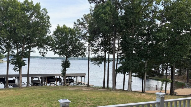 A lakeside view with a dock, covered seating area, and a white fence. - Spacious 4-bedroom, waterfront townhome at Lake Gaston (Henrico)