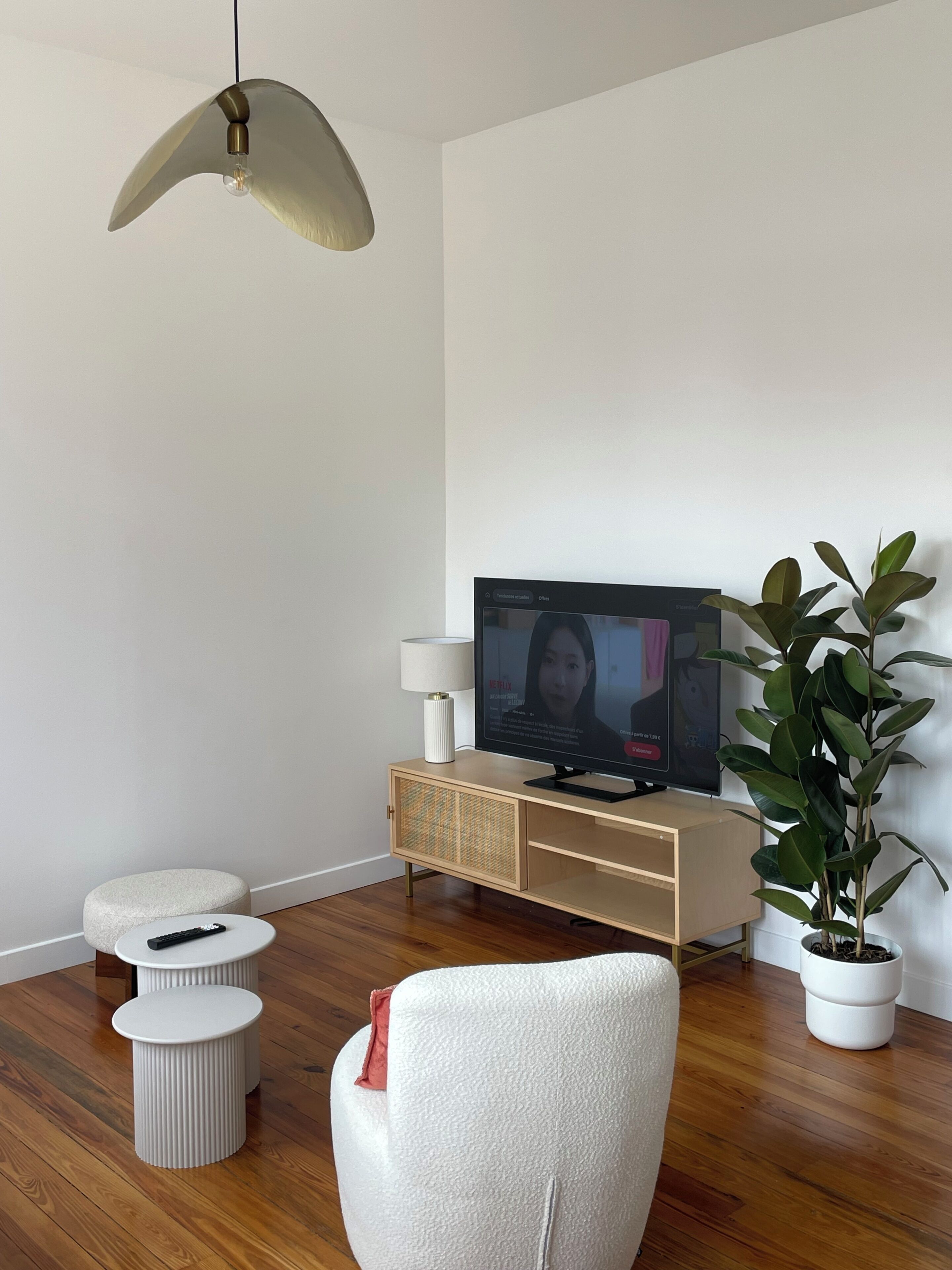 A modern living room with a television, a sofa, a small table, and a potted plant.