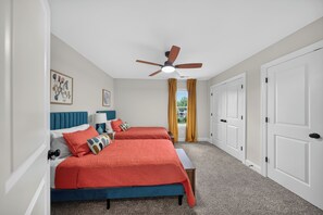 Un dormitorio con dos camas, un ventilador de techo y vistas al exterior a través de una ventana.