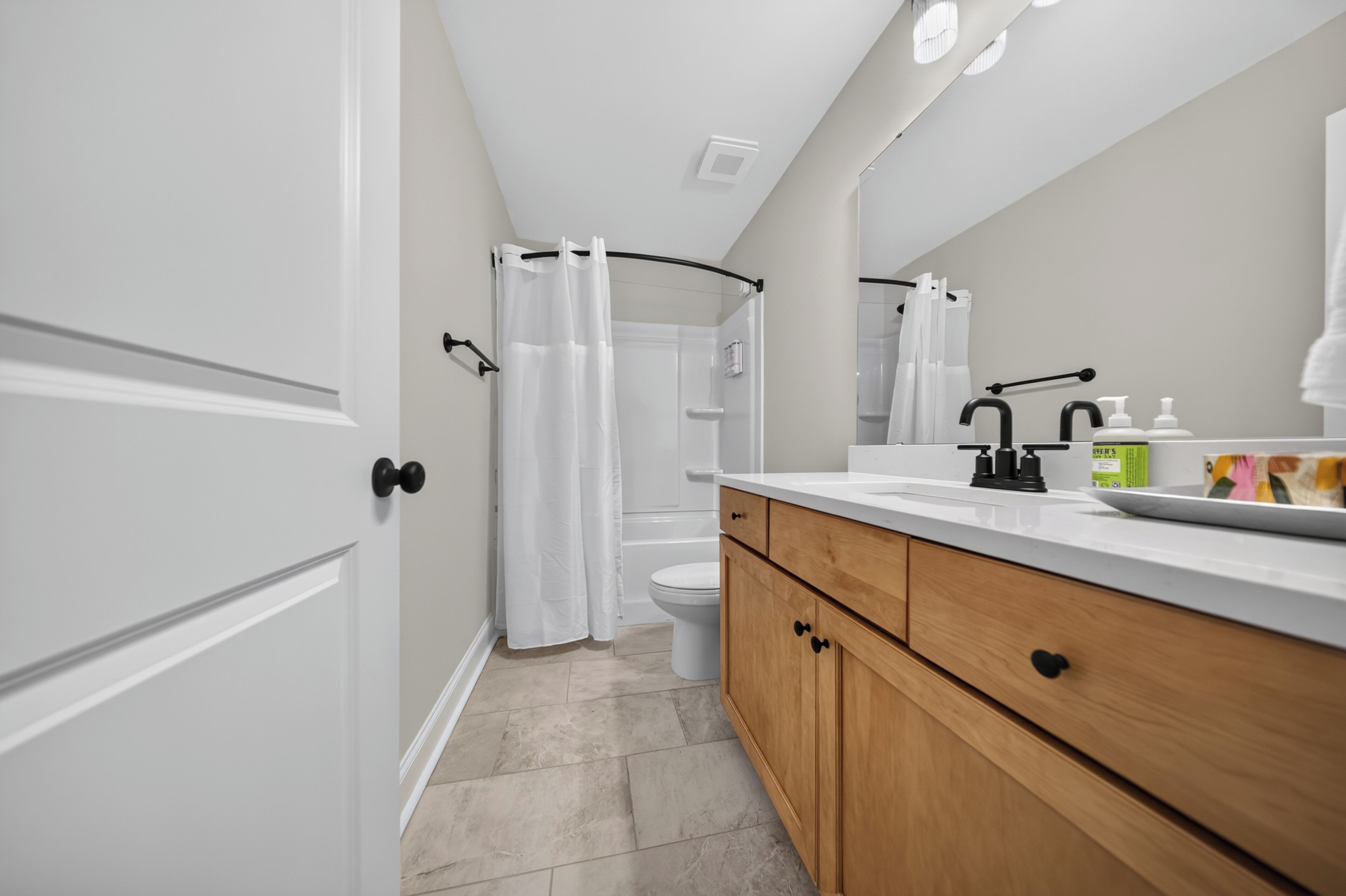 A modern bathroom with a shower, toilet, and vanity with a mirror.