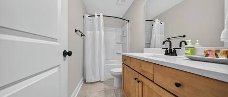 A modern bathroom with a shower, toilet, and vanity with a mirror.