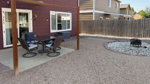 Un espace extérieur aménagé avec une table et des chaises, une pergola en bois et un sol en gravier.