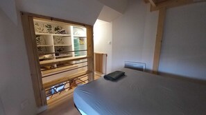 A bedroom with a bed, a wooden shelf unit, and a radiator.