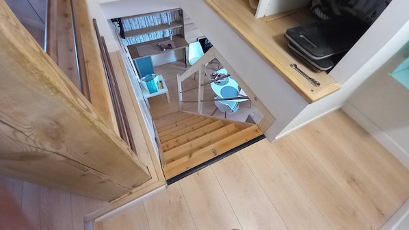 A wooden staircase leading to a dining area with a table and chairs.