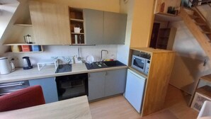 A compact kitchen with a sink, microwave, and a small refrigerator.