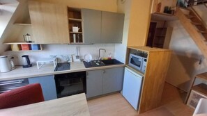 A compact kitchen with a sink, microwave, and a small refrigerator.