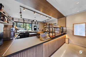Ein modernes Café-Interieur mit einer Theke, auf der Gebäck angeboten wird, und einer Speisekarte.