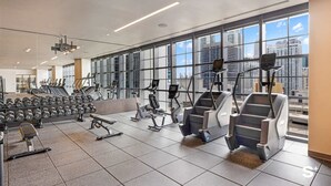 Et moderne fitnesscenter med træningsudstyr, store vinduer og udsigt over byen.