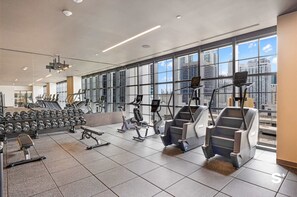 Ein modernes Fitnessstudio mit verschiedenen Trainingsgeräten, großen Fenstern und Blick auf die Stadt.