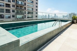A rooftop swimming pool with a city skyline view, surrounded by a glass railing and a potted plant. - Modern studio in the heart of Brooklyn (São Paulo)