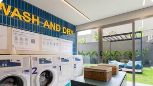 Un espace buanderie avec une pancarte indiquant « LAVAGE ET SÉCHAGE », deux machines à laver et un étendoir.
