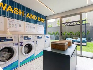 A laundry area with a 'WASH AND DRY' sign, two washing machines, and a drying rack.