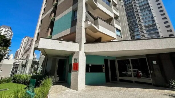 Un immeuble à plusieurs étages, doté d’une façade sobre, de grandes fenêtres et d’un espace d’entrée verdoyant.