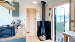 A modern kitchen with a built-in stove, wooden cabinets, and a window.