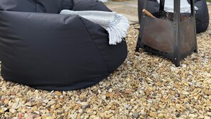 A black outdoor seating area with a fire pit and a covered patio.