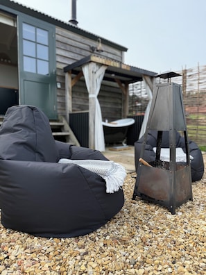 Un área de estar al aire libre con chimenea y un porche cubierto.