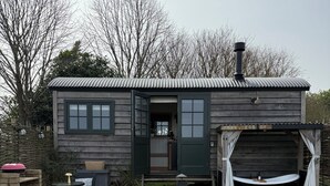 A wooden cabin with a garage, outdoor seating, and a hot tub.