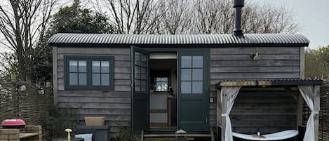 A wooden cabin with a garage, outdoor seating, and a hot tub.