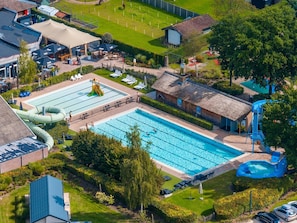 A swimming pool with a slide, lounge chairs, and a small building. - Nature Chalet Near Efteling (Kaatsheuvel)