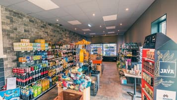 A grocery store interior with shelves stocked with beverages, snacks, and a refrigerated section.