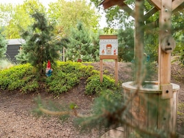 Un jardín con un letrero de madera, una estatua de gnomo y una construcción de madera.