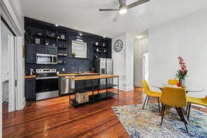 Una cocina moderna con armarios oscuros, una mesa de comedor de madera y un ventilador de techo.