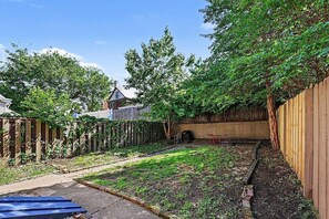 Ein Garten mit Holzzaun, Grill und einem Gartenbereich.