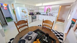 Una cucina moderna con mobili bianchi, un forno a microonde e un fornello. C'è una zona pranzo con un tavolo e sedie in legno.