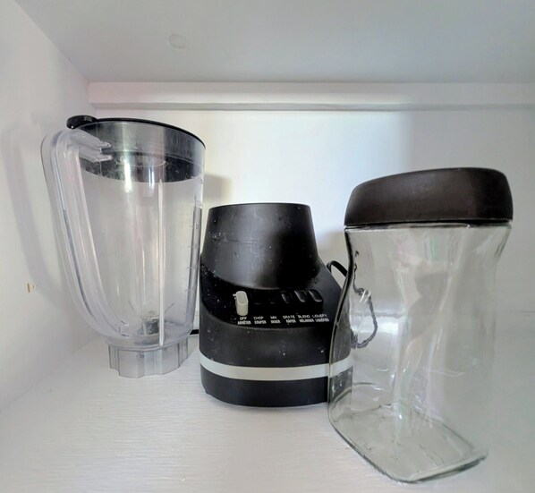 A kitchen shelf with a blender, a glass pitcher, and a glass carafe.