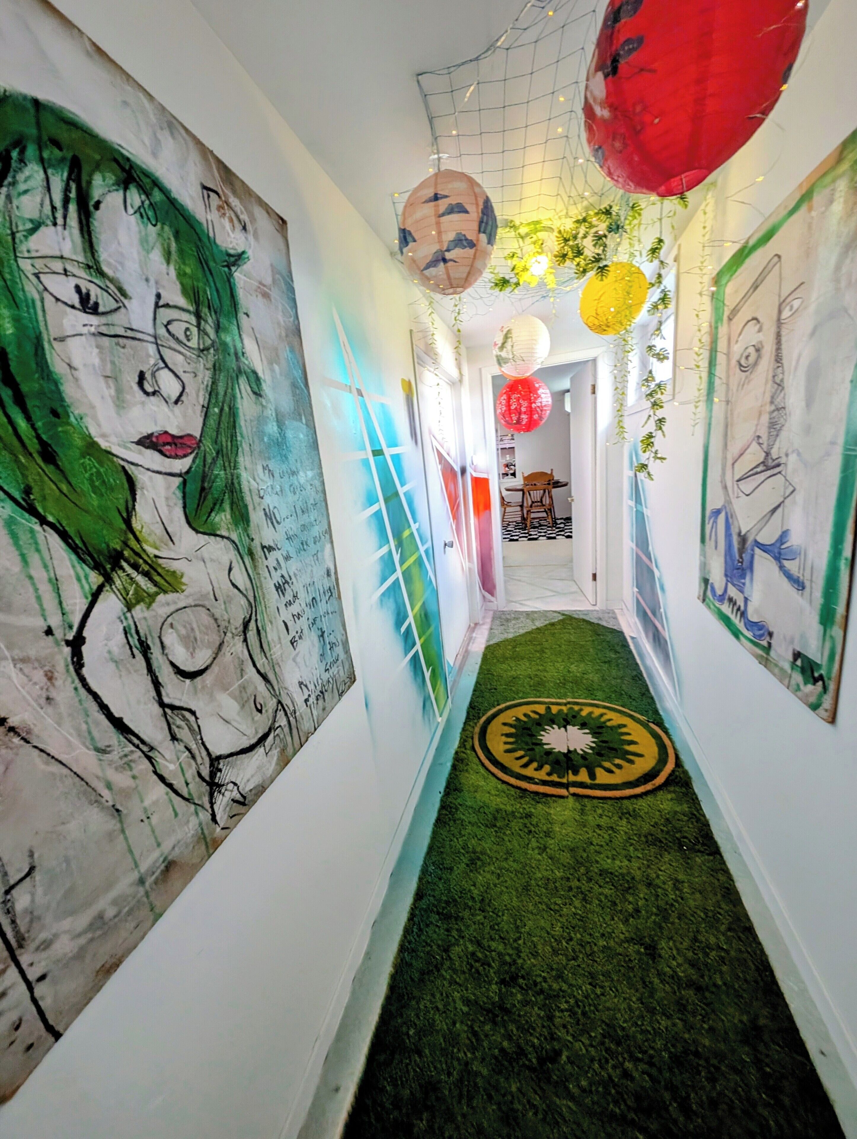 Un passadís amb obra d'art abstracta a la paret, una catifes verda i decoracions penjades.