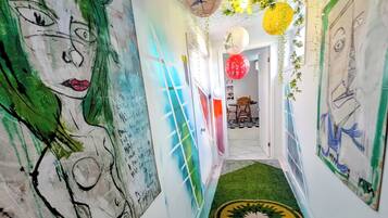 Un passadís amb obra d'art abstracta a la paret, una catifes verda i decoracions penjades.