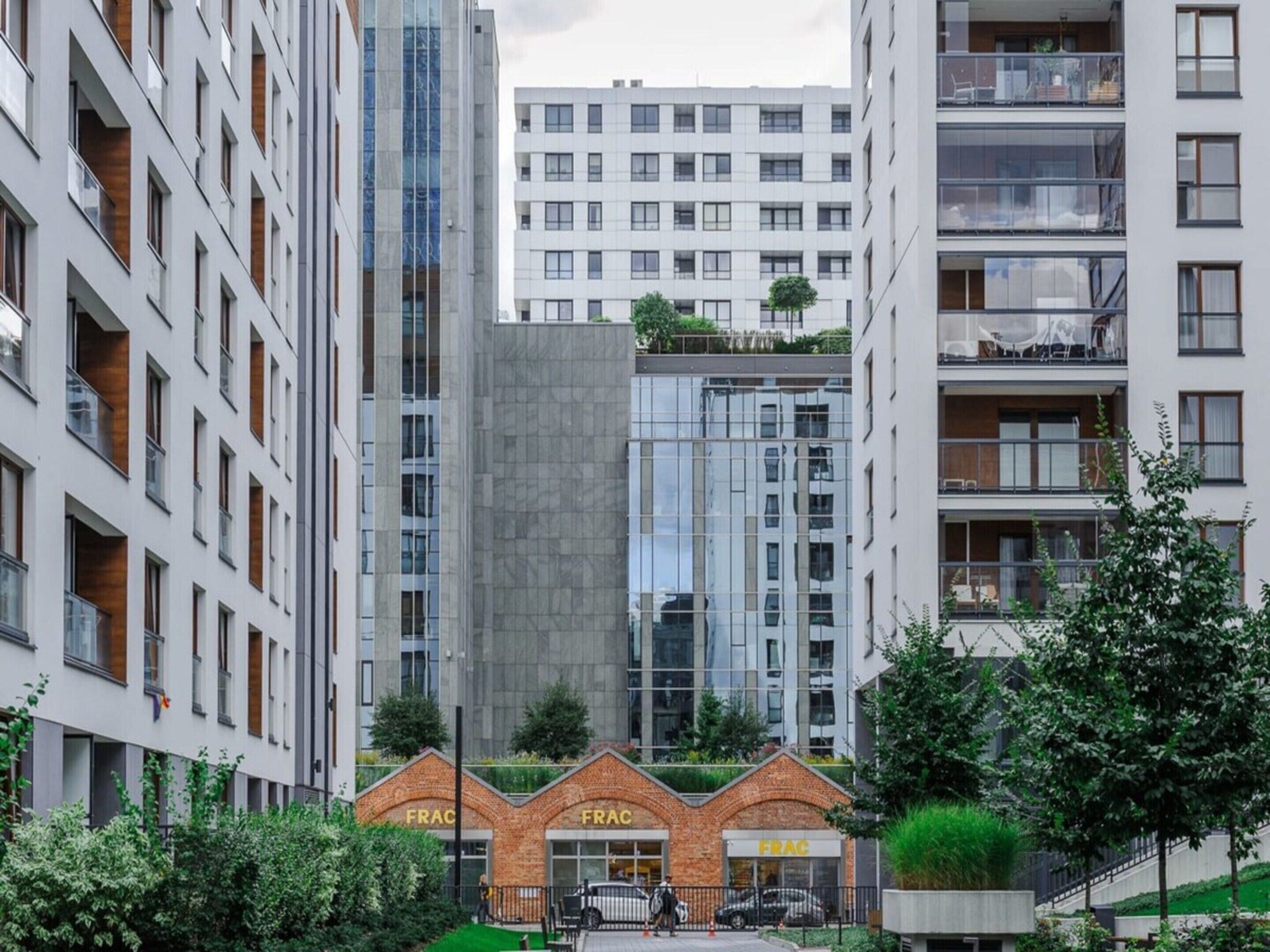 A multi-story building with a modern architectural design, featuring a mix of glass and brick facades, and a ground-level entrance with a sign that reads 'FRAC'.
