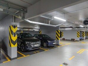 Eine Parkgarage mit zwei Autos, die in ausgewiesenen Stellplätzen stehen, welche durch gelbe Linien und Nummern gekennzeichnet sind.