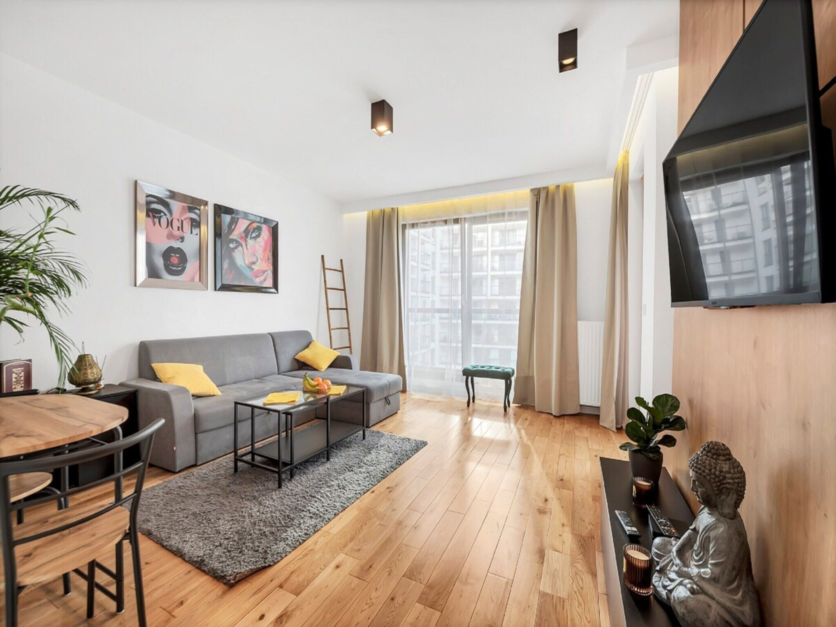 Ein modernes Wohnzimmer mit grauem Sofa, Couchtisch und Essbereich mit Holztisch und Stühlen.