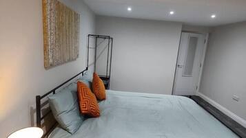 A bedroom with a bed, a bedside table, a lamp, and a wall-mounted artwork.