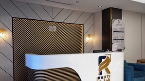 A reception desk with a modern design, a logo, and a wall-mounted information board.
