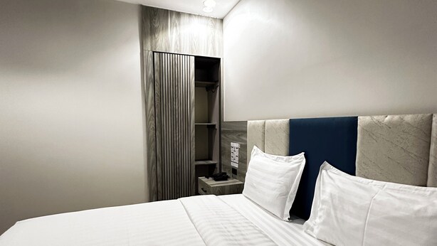 A hotel room with a bed, a nightstand, a wardrobe, and a headboard.