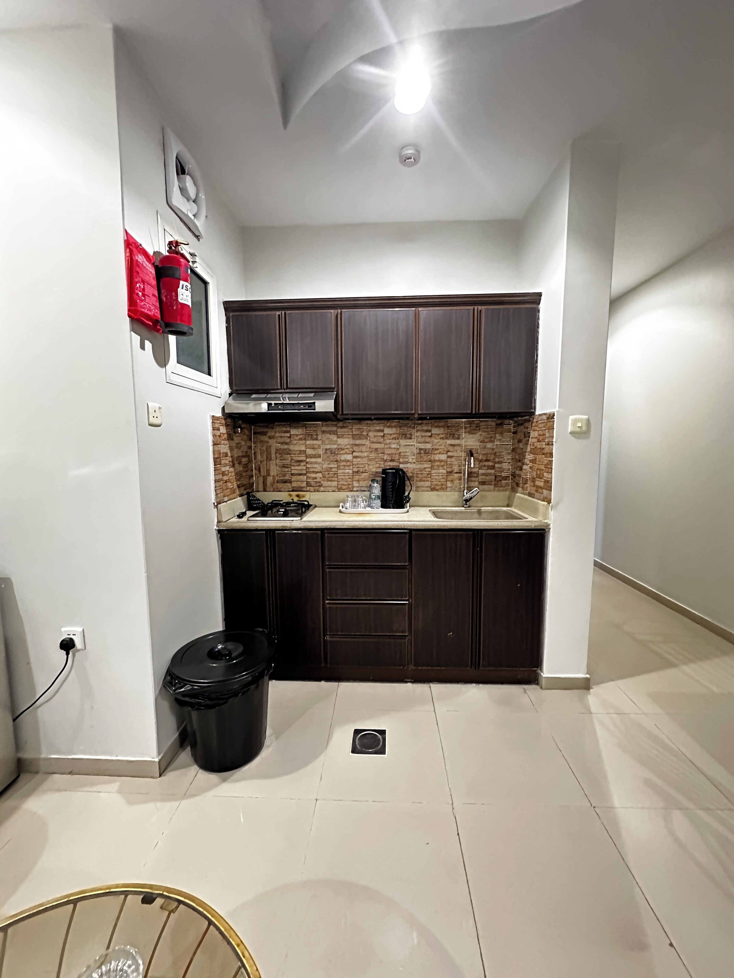 Cocina compacta con armarios de madera oscura, salpicadero de azulejos y campana extractora de acero inoxidable.