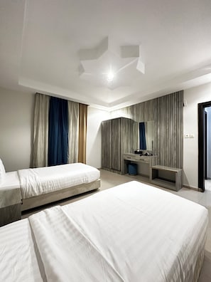 A hotel room with two beds, a vanity with a mirror, and a large window with curtains.