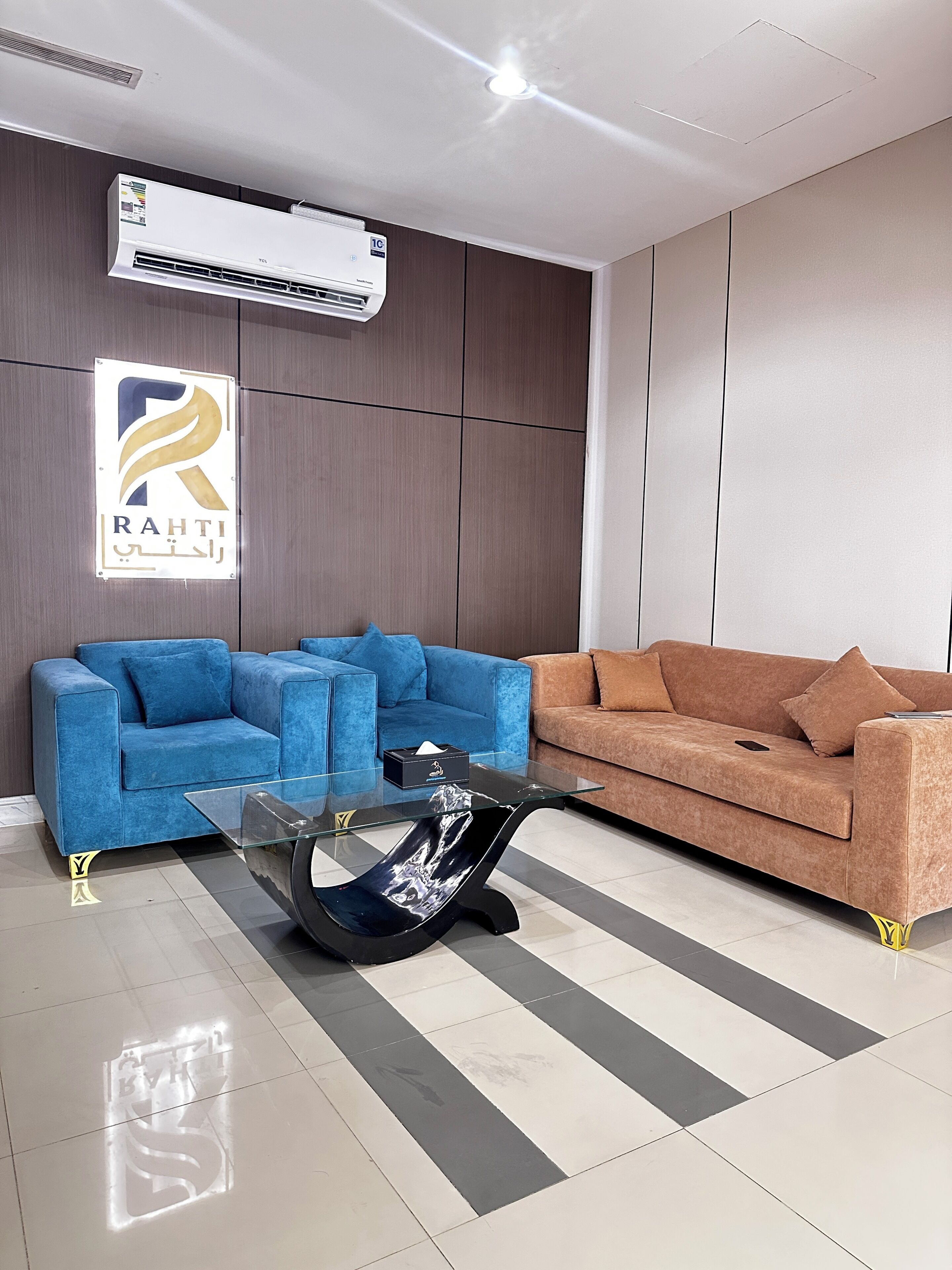 A modern living room with two sofas, a glass coffee table, and an air conditioning unit.