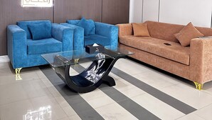 A modern living room with two sofas, a glass coffee table, and an air conditioning unit.