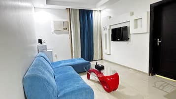 A modern living room with a sectional sofa, a red coffee table, a television, and a door.