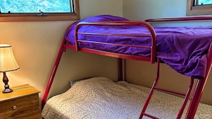 A bunk bed with a ladder, a wooden dresser, and a window with a view of trees. - Lake Alexander Hideaway - Waterfront, Private Dock (Cushing)