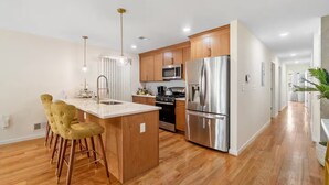 Una cocina moderna con armarios de madera, electrodomésticos de acero inoxidable y una isla central con taburetes de bar.
