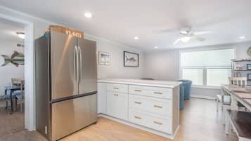 A modern kitchen with a stainless steel refrigerator, white cabinetry, and a dining area with a table and chairs.