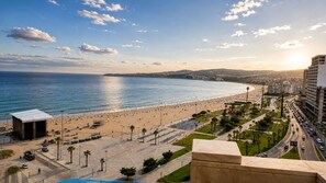 A coastal cityscape with a wide beach, a road parallel to the shore, and a large building on the right. - Luxury Oceanfront Property with Views of Tangier Bay (Tánger)