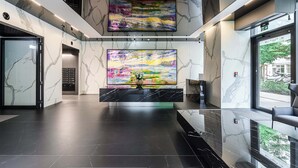 A lobby with marble walls, a black reception desk, and a large abstract painting. - Warsaw Flat With Balcony (Warsaw)