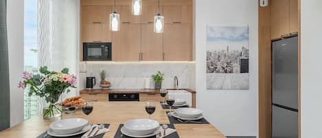 A modern kitchen with wooden cabinets, a built-in microwave, and pendant lighting.