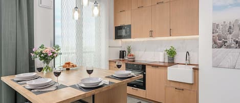 Una cocina moderna con armarios de madera, microondas integrado y una zona de comedor con mesa para dos.